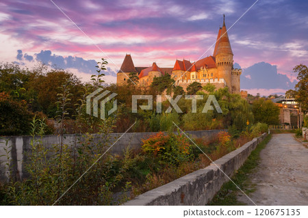 hunedoara, romania - 13 oct, 2019: corvin castle at sunrise. old fortress with tower. path through wonderful location in fall season hunedoara, romania - 13 oct, 2019: corvin castle at sunrise. old fortress with tower. path through wonderful location in fall season 120675135