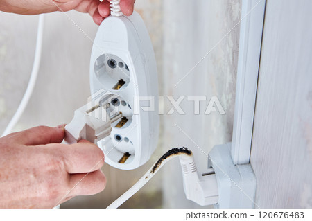 Burnt extension cord with plug still connected to outlet. Burnt extension cord with plug still connected to outlet. 120676483