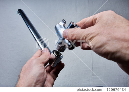 Upright longest swivel long neck mixer tap part of faucet with shower valve in plumber hands on grey background. 120676484