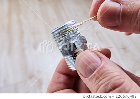 Winding flax on pipe thread and leak seal with mounting plumbing paste. Winding flax on pipe thread and leak seal with mounting plumbing paste. 120676492