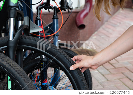 Person checking air pressure of bicycle tire on brick pavement. 120677445