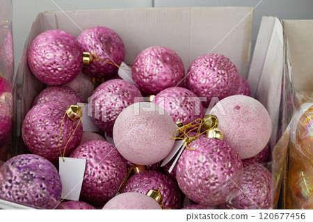 Colorful decorative Christmas ornaments in a box filled with pink shades. 120677456