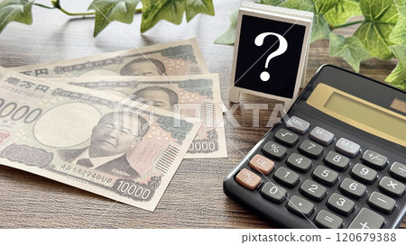 新的 10,000 日元鈔票和帶有問號和計算器_棕色板背景的迷你招牌 新的 10,000 日元鈔票和帶有問號和計算器_棕色板背景的迷你招牌 120679388