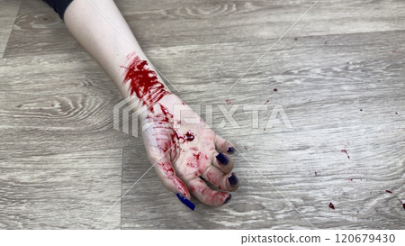 Hand in blood of dead girl on floor of apartment has cuts after committing crime. Bloody marks on body hand after brutal murder of woman. Investigating crime after finding dead person 120679430