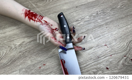 Close up photo of girl bloody hand with bloody knife on floor. Traces of blood in crime scene with knife. Murder of girl and murder weapon on floor of apartment 120679431