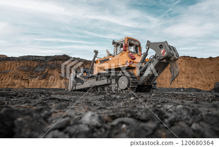 Yellow excavator in career moves overburden. Bulldozer working in an open pit. Bulldozer combs the ground, with the bright sun and nice blue sky in the background. Mining digger, mining machinery 120680364