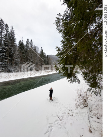 Person on Snowy Riverbank with Forest and Bridge Person on Snowy Riverbank with Forest and Bridge 120681088