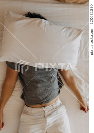 Sleepy man keep on sleeping on the bed, using pillow covering his face. Sleepy man keep on sleeping on the bed, using pillow covering his face. 120681850