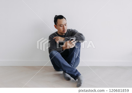 Creative freelance man sitting on the floor looking at the phone. 120681859