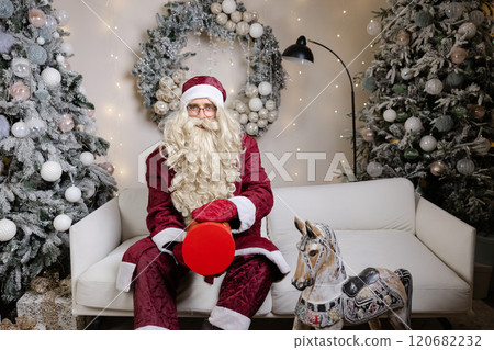 Santa claus juggling with a gift box in christmas decorated living room Santa claus juggling with a gift box in christmas decorated living room 120682232