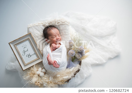 Newborn photo_A happy newborn baby wrapped in a swaddling cloth, smiling and sleeping peacefully 120682724