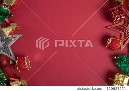 Festive Christmas decorations on bright red background, gifts, baubles, mini tree, stars, bells and drum ornaments 120683251