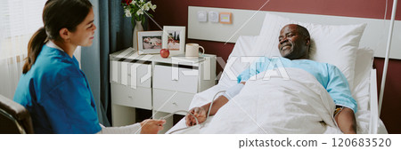 Healthcare professional attending to elderly patient in bed at medical facility, patient lying down, receiving professional care and looking comfortable Healthcare professional attending to elderly patient in bed at medical facility, patient lying down, receiving professional care and looking comfortable 120683520