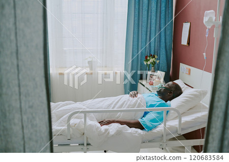 African American patient resting in hospital bed receiving medical care surrounded by medical equipment and soothing decor creating a calm atmosphere African American patient resting in hospital bed receiving medical care surrounded by medical equipment and soothing decor creating a calm atmosphere 120683584