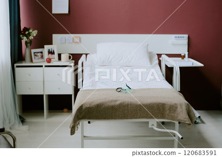 Empty hospital bed with medical equipment and a nightstand in a clean, well-lit room with beige walls, displaying a serene and orderly atmosphere Empty hospital bed with medical equipment and a nightstand in a clean, well-lit room with beige walls, displaying a serene and orderly atmosphere 120683591
