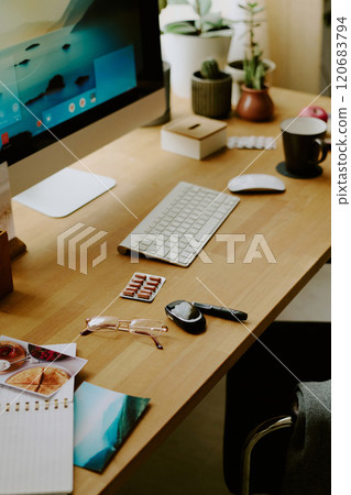 Modern workspace featuring a large desktop computer, wireless keyboard, plants and coffee cup adding touch of greenery and relaxation 120683794