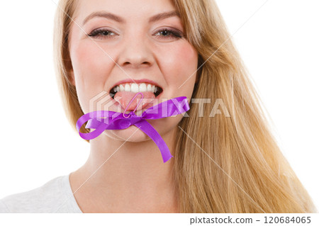 Blonde woman biting decorative purple bow 120684065