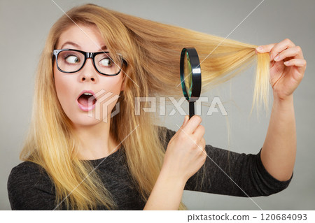 Woman holding magnifying glass looking at hair 120684093