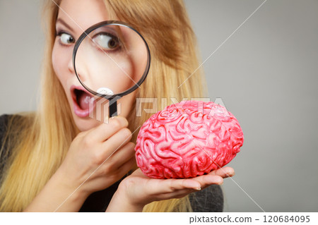 Woman holding magnifying glass investigating brain Woman holding magnifying glass investigating brain 120684095