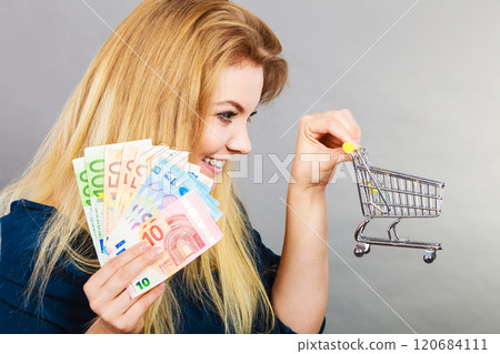Happy woman holding shopping cart with money Happy woman holding shopping cart with money 120684111