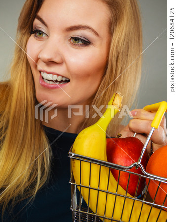 Woman holding shopping basket with fruits inside 120684125