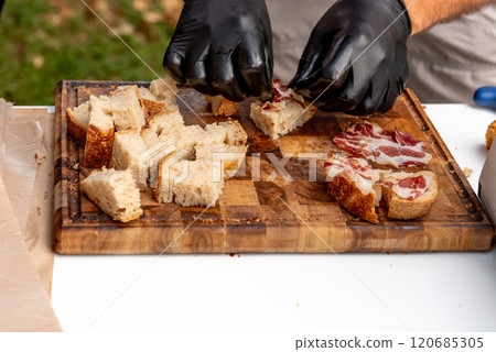 cutting bread and ham on wooden cutting board for tasting 120685305