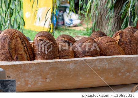 three sourdough whole grain loaf of bread in the wooden trough on food market. 120685325