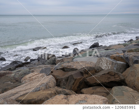 resort in winter. The rocky shore is washed by the waves in cloudy weather. Black Sea coast. The coast of Batumi. Nature in shades of grey. boring landscape 120685991