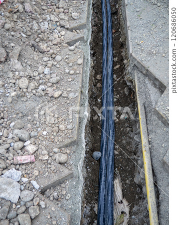 Broken sidewalk. Conducting the cable underground. Cable laying work. Communications in the city.  Dig trench for wires. 120686050