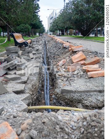 Broken sidewalk. Conducting the cable underground. Cable laying work. Communications in the city. Digging a trench for wires. Broken sidewalk. Conducting the cable underground. Cable laying work. Communications in the city. Digging a trench for wires. 120686051