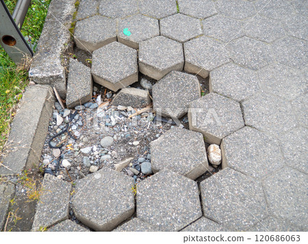 Broken paving stone. Hexagonal block. Sidewalk needs repair. 120686063