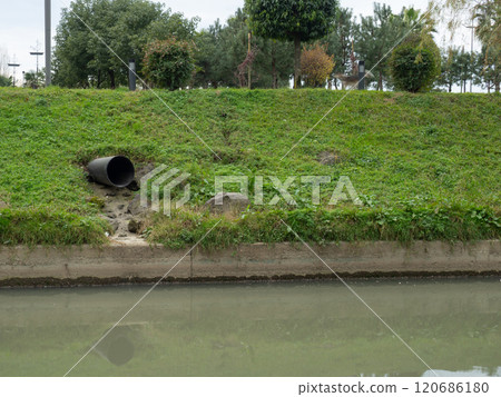 The pipe sticks out of the slope. Drainage of water from stormwater into the river.  Drainage system in the city. 120686180