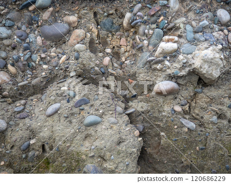 Layers of earth on a beach made of pebbles. Soil cut. Cobblestones and earth. After the excavator. 120686229
