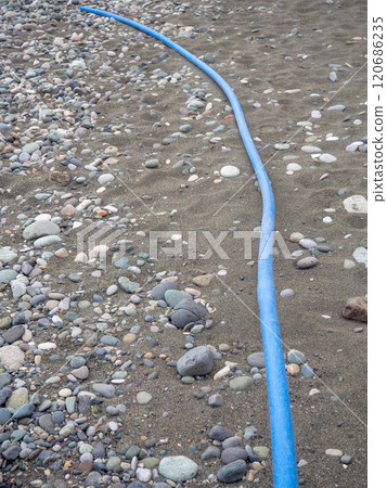 Cable on black sand. The cable sticks out of the ground. Electrical communications on the beach. Industry. Cable on black sand. The cable sticks out of the ground. Electrical communications on the beach. Industry. 120686235