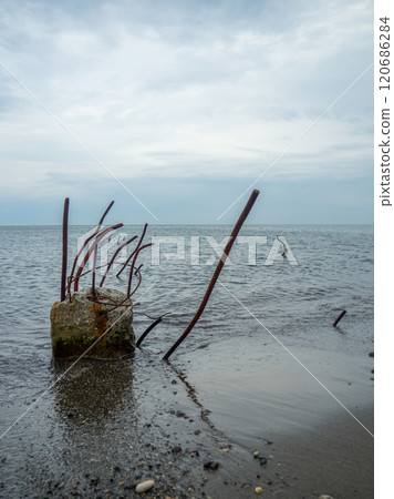 Reinforced concrete sticking out of the water. Remains of the structure. Abandoned. Armature at sea. A pile driven into the bottom of the sea. Reinforced concrete sticking out of the water. Remains of the structure. Abandoned. Armature at sea. A pile driven into the bottom of the sea. 120686284