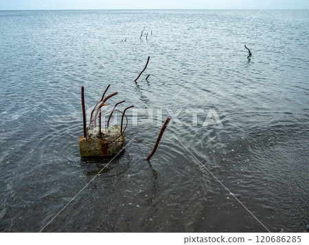Reinforced concrete sticking out of the water. Remains of the structure. Abandoned. Armature at sea. A pile driven into the bottom of the sea 120686285