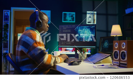 Black man programmer manages code and scripts in artificial intelligence and machine learning on dual monitors pc. Male freelancer uses personal computer to guarantee cyber security. Camera B. Black man programmer manages code and scripts in artificial intelligence and machine learning on dual monitors pc. Male freelancer uses personal computer to guarantee cyber security. Camera B. 120686553