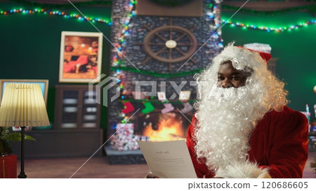 Saint Nick reading Christmas letters in his cozy cabin at the North Pole, surrounded by festive decorations and twinkling lights. Tradition and magic bring the holiday cheer to life. Camera B. 120686605