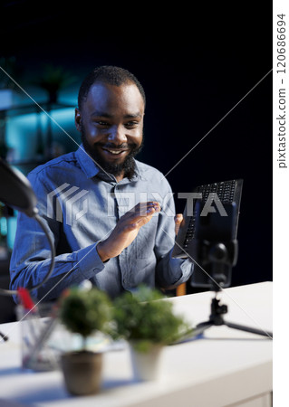 African american internet show host hitting the record button on smartphone on phone holder, filming content. Media star recording gaming keyboard review for niche audience African american internet show host hitting the record button on smartphone on phone holder, filming content. Media star recording gaming keyboard review for niche audience 120686694