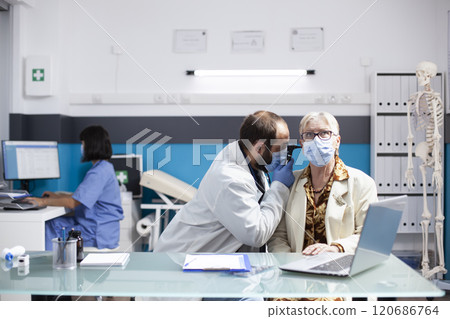 Young doctor inspects ear of female pensioner patient with professional care, checking for infection using otology equipment. Male physician holds otoscope and performs hearing test on retired woman. Young doctor inspects ear of female pensioner patient with professional care, checking for infection using otology equipment. Male physician holds otoscope and performs hearing test on retired woman. 120686764