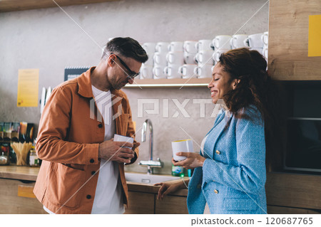 Smiling diverse couple with coffee in kitchen Smiling diverse couple with coffee in kitchen 120687765