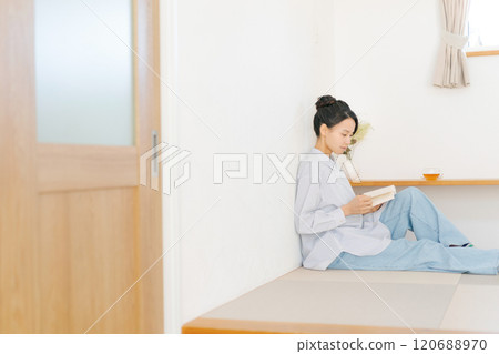 A woman sitting in a Japanese-style room and reading a book 120688970