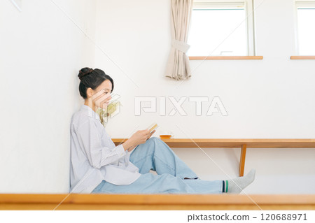 A woman sitting in a Japanese-style room and reading a book 120688971
