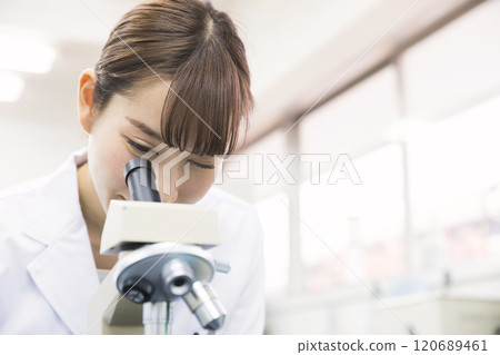 研究開發實驗圖像一位年輕的女性研究員，通過顯微鏡看 120689461