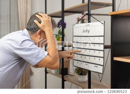 Confused Asian Senior Man With Dementia Looking At Wall Calendar. Confused Asian Senior Man With Dementia Looking At Wall Calendar. 120690523