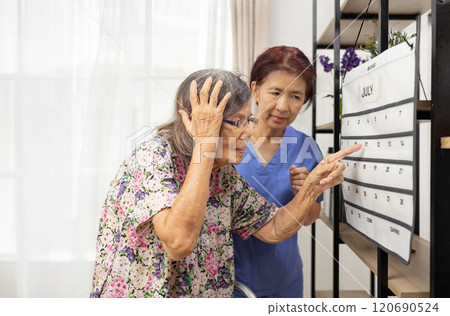 Confused Asian Elderly Woman With Dementia Looking At Wall Calendar. Confused Asian Elderly Woman With Dementia Looking At Wall Calendar. 120690524