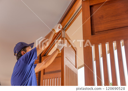 Handyman fixing bifold doors sticking or not sliding properly. 120690528