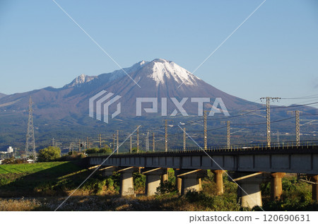 A JR Sanin Main Line bridge crossing the Hino River towards the foot of Mt. Daisen, covered with its first snow. 120690631