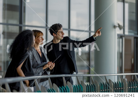 Diverse group businesspeople walking to meeting at modern office. Businessmen and businesswoman chatting talk with tablet and document paper. Manager orders work on way to office. 120691241