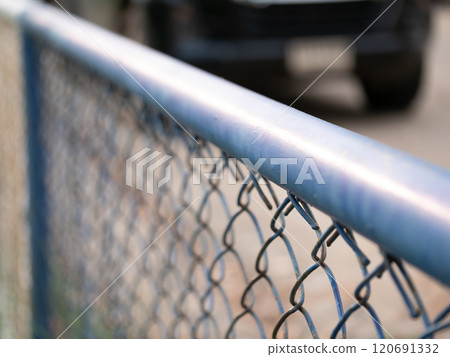 Close-up view of chain link fence with car in background urban setting photography outdoor perspective security concept 120691332
